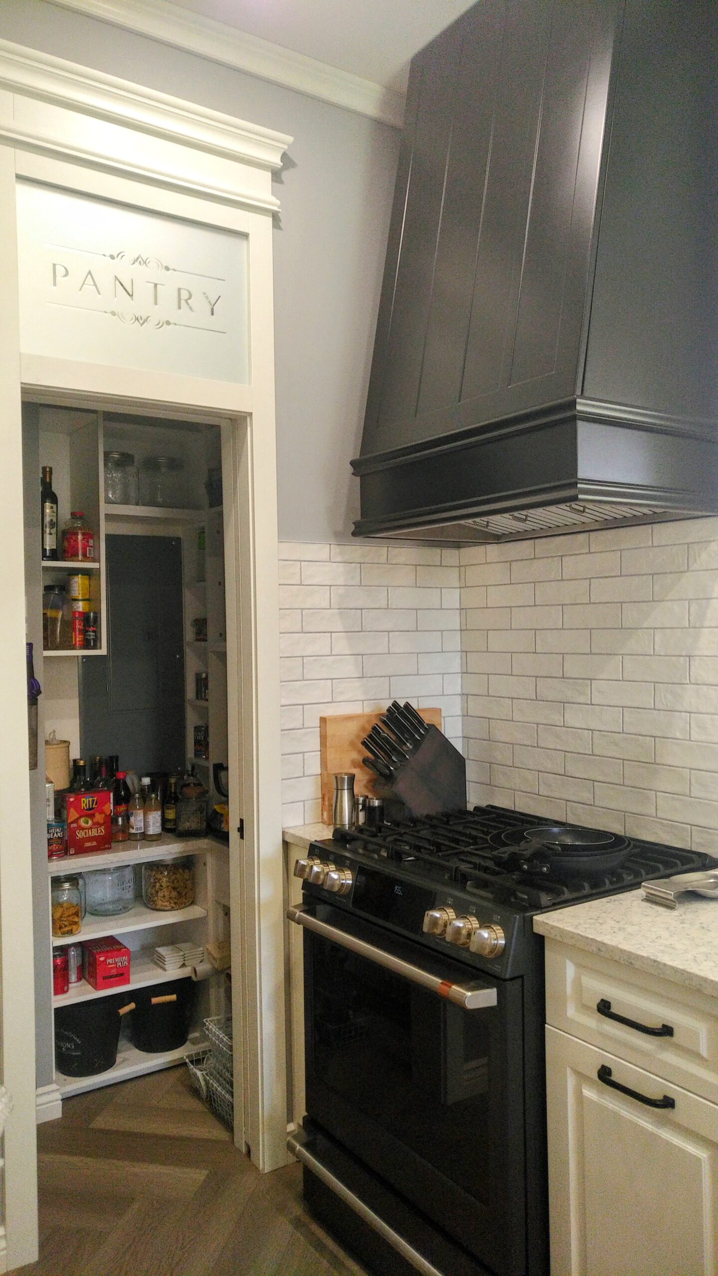 custom range hood, frosted pantry, small pantry, white backsplash, white raised panel cabinets,